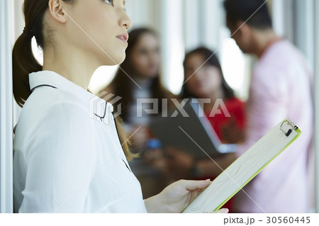A businesswoman is holding documents and looking up. A businesswoman is holding documents and looking up. 30560445