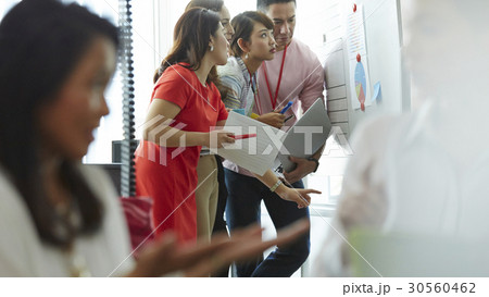 Four of five staff are looking at a board Four of five staff are looking at a board 30560462