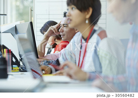 A man is smiling and thinking next to some working people A man is smiling and thinking next to some working people 30560482