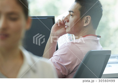 A businessman talking on mobile phone at office A businessman talking on mobile phone at office 30560499