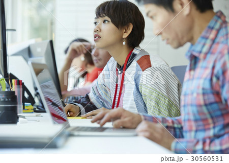 A woman is looking at something while colleagues are working 30560531