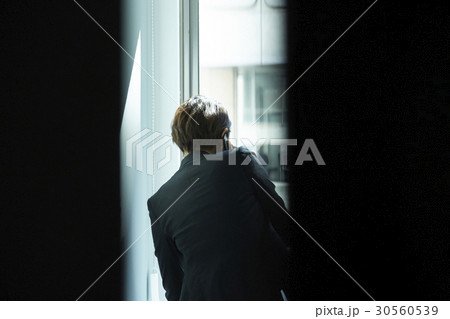 A person is talking on phone next to a window 30560539