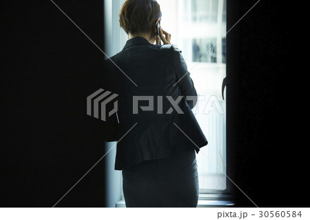 Rear view of a businesswoman talking on phone in office. 30560584