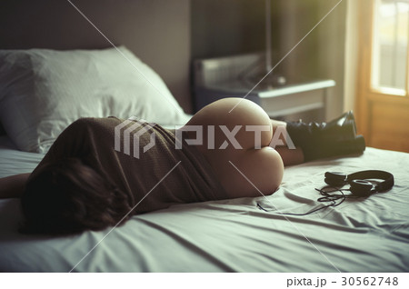 Beautiful naked girl lies on a bed in headphones  30562748