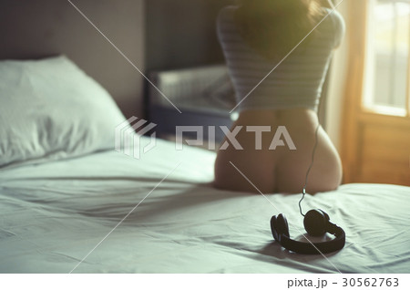 Beautiful naked girl lies on a bed in headphones  30562763