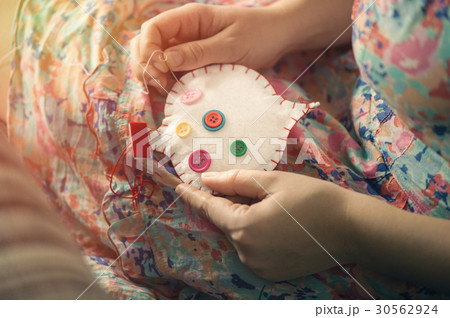 Female hands sew white cotton heart with buttons 30562924
