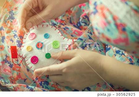 Female hands sew white cotton heart with buttons Female hands sew white cotton heart with buttons 30562925