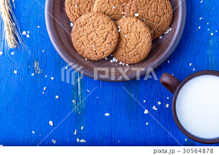 Oatmeal cookies in brown plate near cup of milk on Oatmeal cookies in brown plate near cup of milk on 30564878