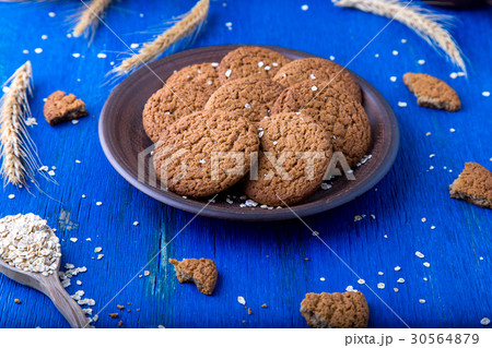 Oatmeal cookies in brown plate on blue background Oatmeal cookies in brown plate on blue background 30564879