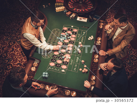Upper class friends gambling in a casino 30565372
