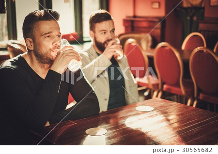 Friends watching TV and drinking draft beer in pub Friends watching TV and drinking draft beer in pub 30565682