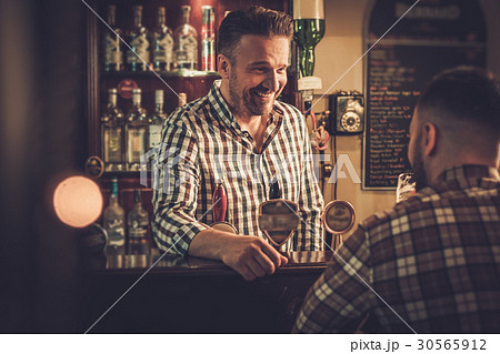 Man chatting with a bartender in a pub 30565912