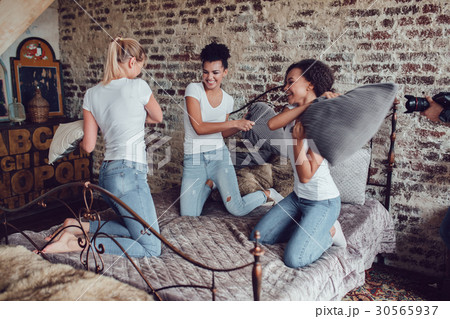 Attractive girls have fun and fight pillows on the 30565937