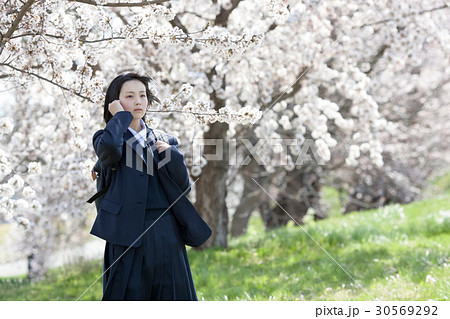 制服を着て桜の木の前に立つ女子高生 30569292
