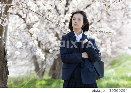 制服を着て桜の木の前に立つ女子高生 30569294