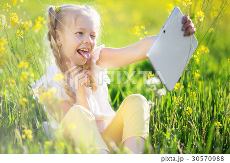Little blonde girl taking selfie in yellow field 30570988
