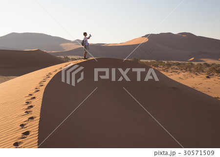 Tourist walking on the dunes of Sossusvlei 30571509