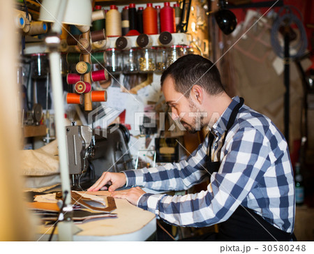 Male worker stitching new belt 30580248