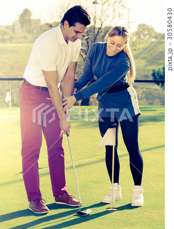 Woman golfer training man to play golf 30580430