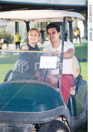 Adult man and woman golfers riding golf cart Adult man and woman golfers riding golf cart 30580455