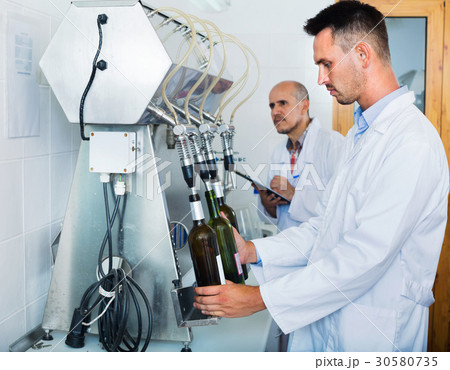 Portrait of male winery worker with bottling machinery on factory Portrait of male winery worker with bottling machinery on factory 30580735