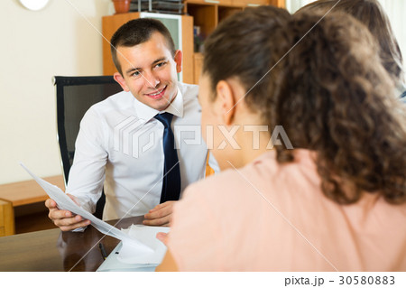 Agent with laptop and young couple. Agent with laptop and young couple. 30580883