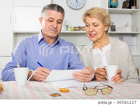 friendly mature couple at table attentively study documents friendly mature couple at table attentively study documents 30581227