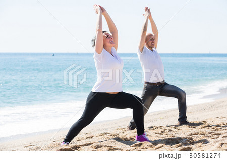 man and woman exercising together on the beach 30581274