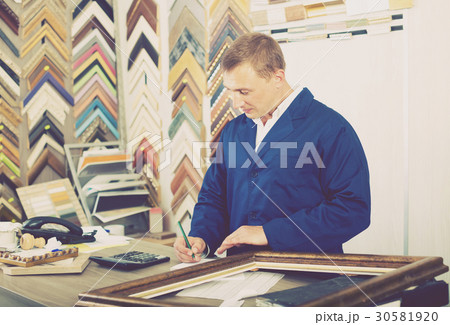 portrait of man seller working with picture frames in atelier 30581920