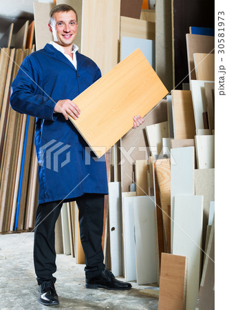 portrait of man in uniform choosing compressed densified wood in picture framing atelier 30581973