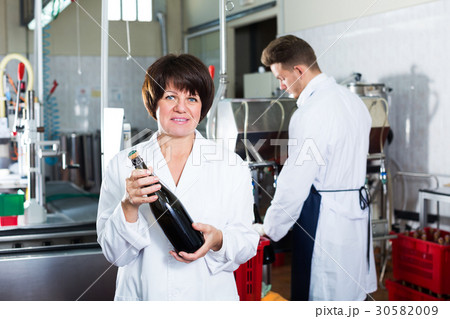Woman worker displaying wine bottle Woman worker displaying wine bottle 30582009