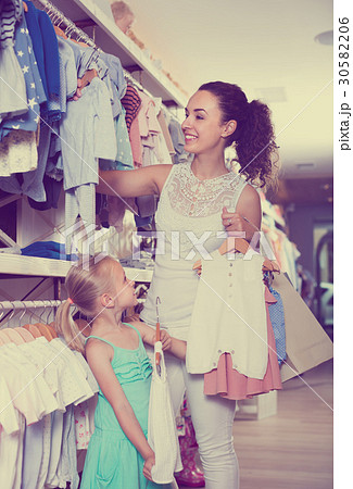 interested mother with daughter buying baby pajamas in kids sect 30582206