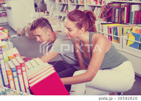girl and boy teenagers in book store. girl and boy teenagers in book store. 30582620