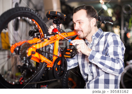smiling male mounts bicycle parts for assembly bike in shop smiling male mounts bicycle parts for assembly bike in shop 30583162