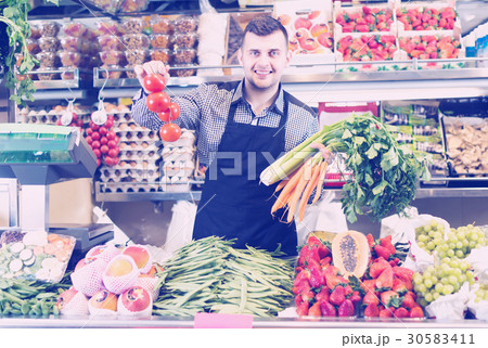 friendly man seller showing assortment of grocery shop friendly man seller showing assortment of grocery shop 30583411