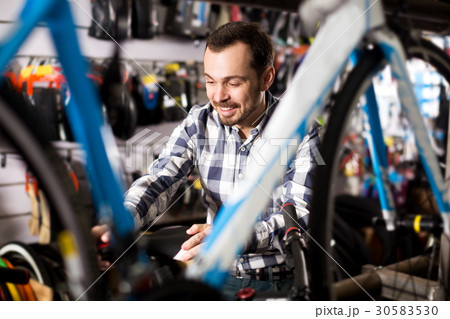 Man considers bicycle frame in store 30583530