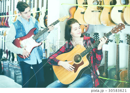 Teenagers examining both electric and acoustic guitars 30583621