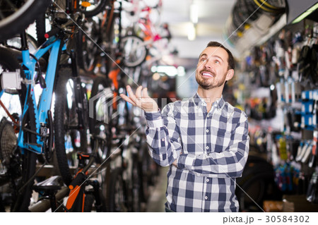 joyous man in bicycle shop chooses for himself sports bike joyous man in bicycle shop chooses for himself sports bike 30584302