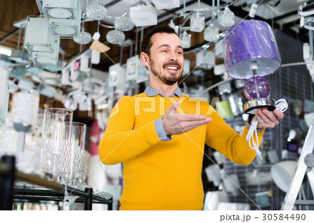 Man in shop of home appliances choosing modern and stylish lamp 30584490