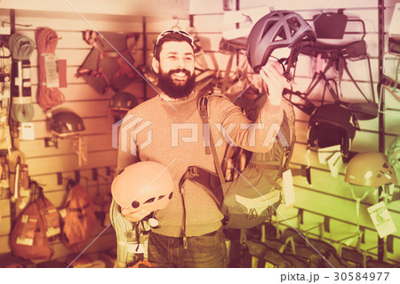 male customer examining helmets in sports equipment store male customer examining helmets in sports equipment store 30584977