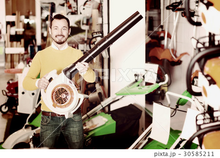 Customer examining leaf blowers in garden equipment shop Customer examining leaf blowers in garden equipment shop 30585211
