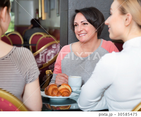 Group of women taking a conversation over a cup of coffee Group of women taking a conversation over a cup of coffee 30585475