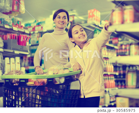 Woman with girl looking for food in supermarket Woman with girl looking for food in supermarket 30585975