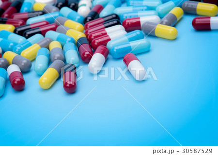 many scattered Colorful pills on blue background. 30587529