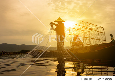 fisherman on wooden boat casting net for fish 30593690