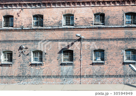 wall of prison with barred windows 30594949