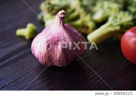 Broccoli, tomatoes and garlic lying on a dark Broccoli, tomatoes and garlic lying on a dark 30600225