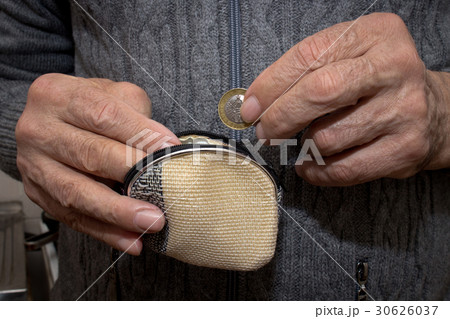 An elderly man in a hand holds a coin and a wallet 30626037