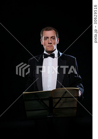 Orchestra conductor in black tuxedo in dark studioの写真素材 [30629516] - PIXTA