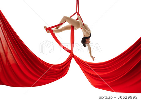 Young girl exercises on red aerial silks in studio 30629995